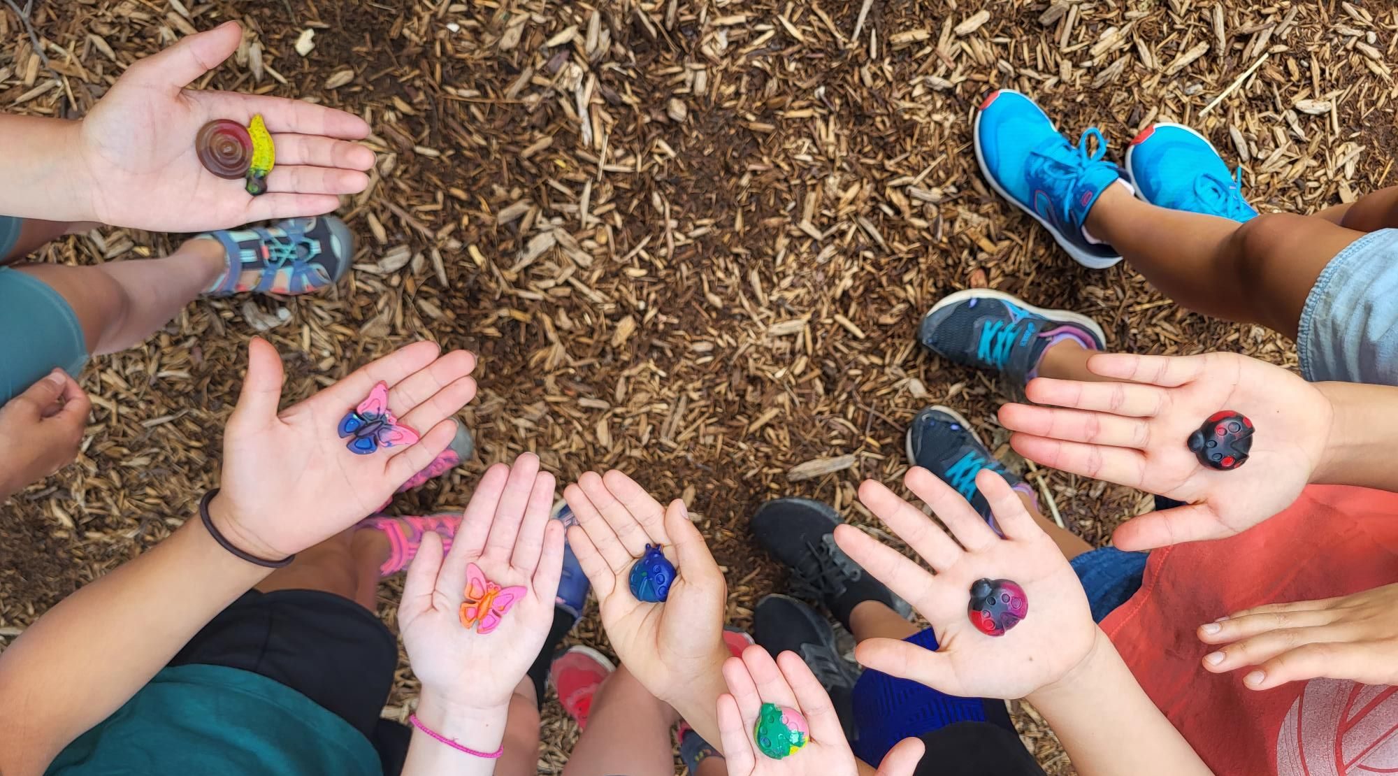 Kids showing clay insect crafts in the palms of their hands.