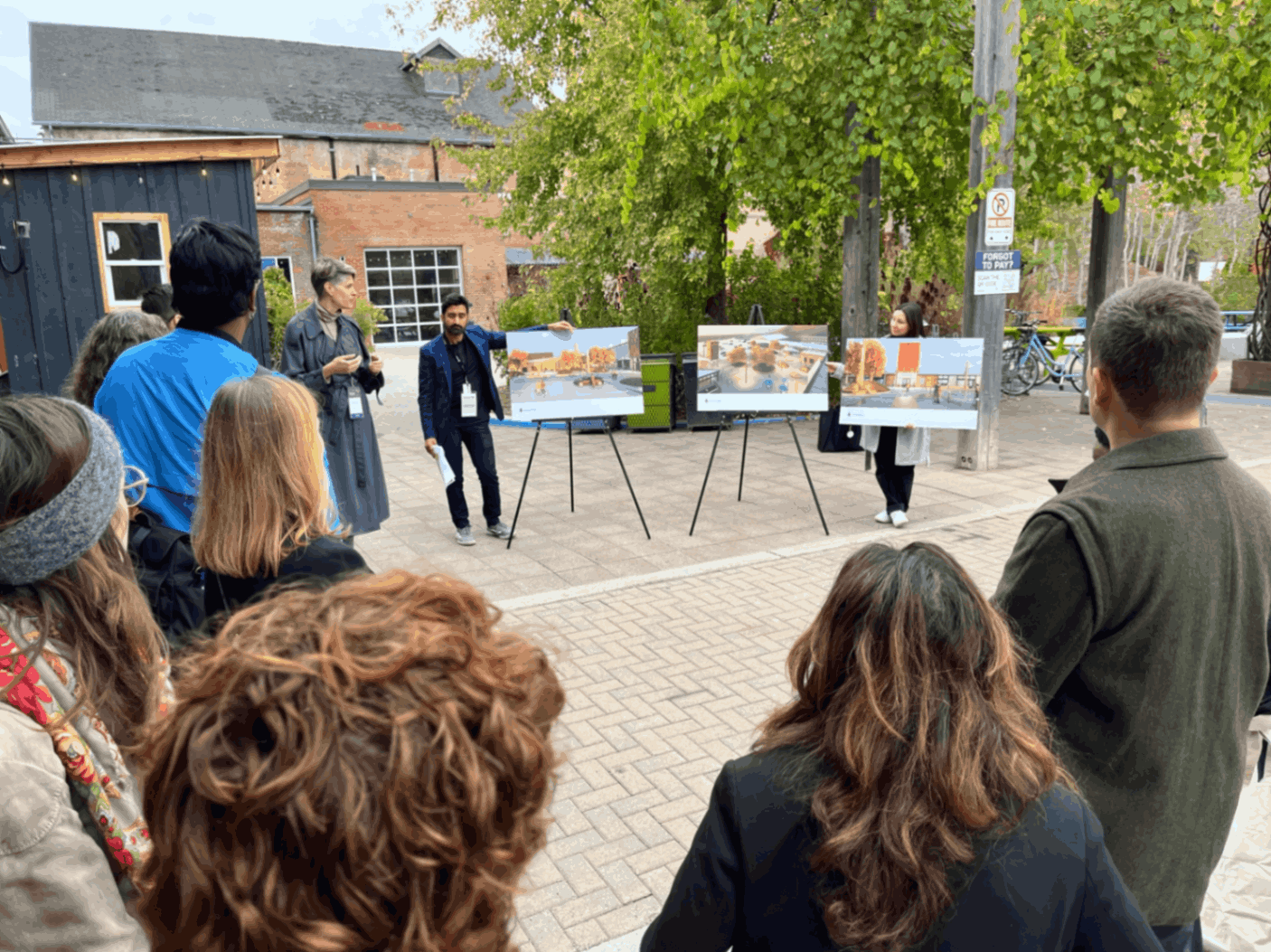 A crowd gathers around renderings showing future plans for Evergreen Brick Works