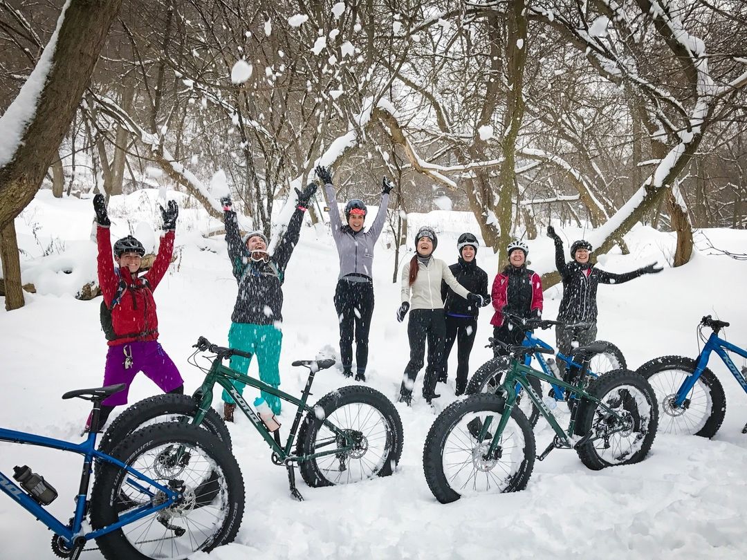 group of people with bikes in the snow on a trail