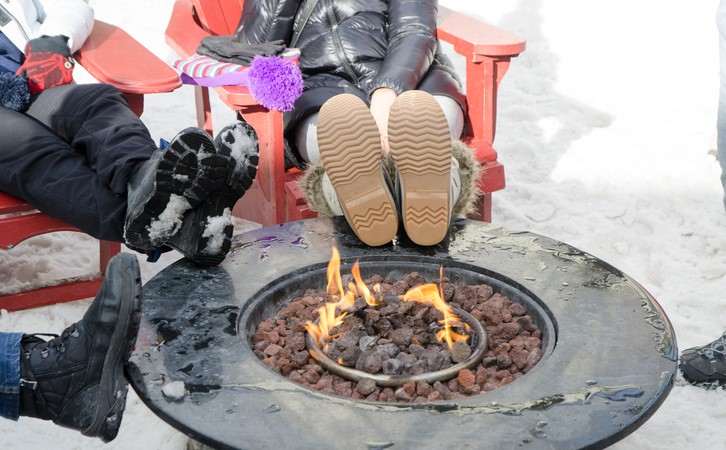 People around outdoor fire pit in the winter, put feet up close to flame