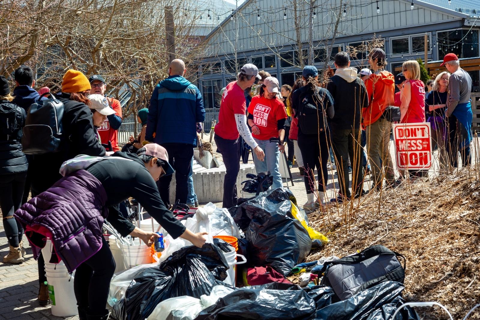 group of people are collecting garbage as part of earth month clean up