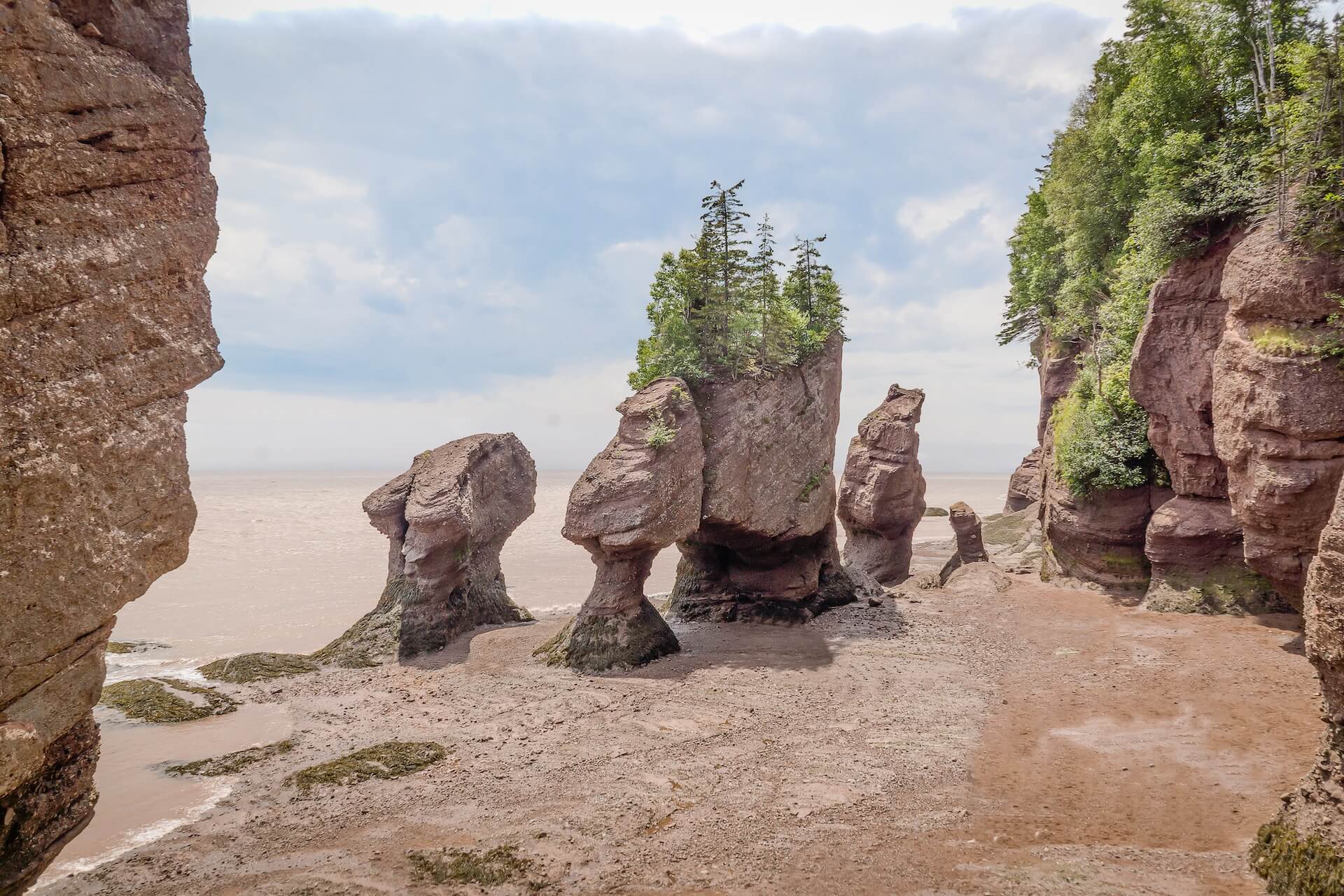 Large rock formations coming up from the water on a beach