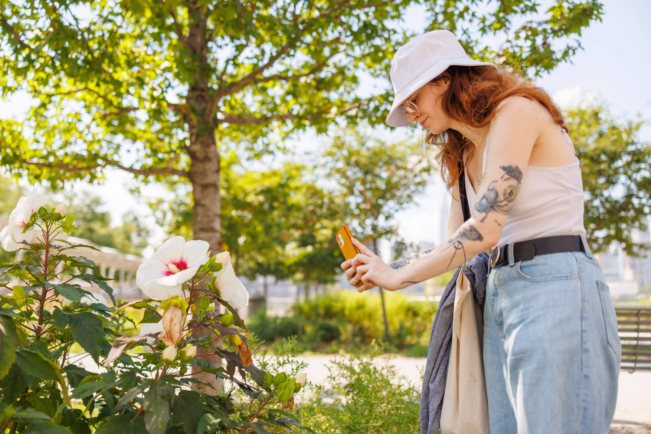 Woman takes photo with her phone of flowers and plants in public park