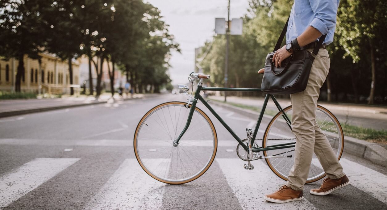 Man walks across city streen with bicyle