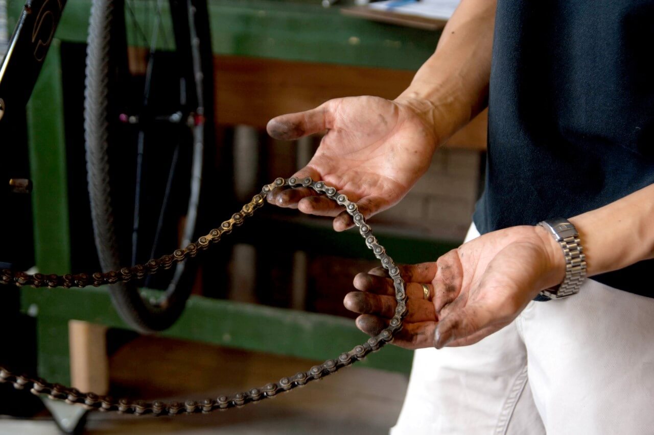 Man holds bicycle chain upclose dirty hands and chain
